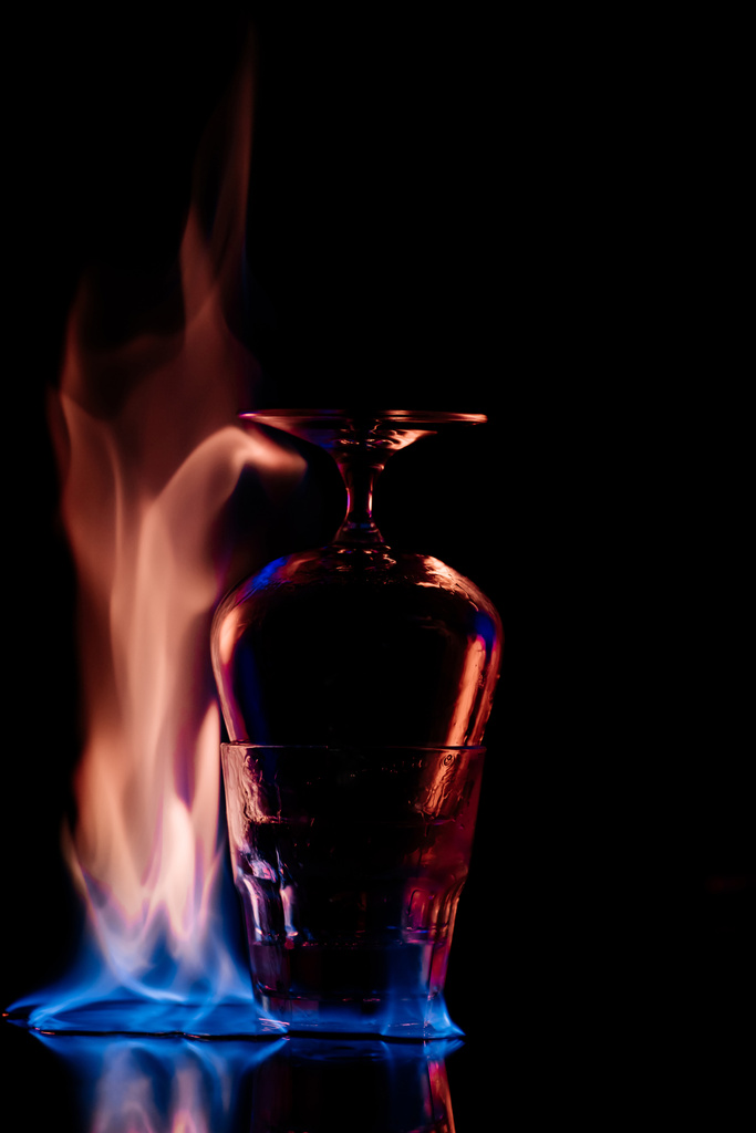 Nahaufnahme von Gläsern und brennendem Sanbuca-Alkohol auf schwarzem Hintergrund - Foto, Bild