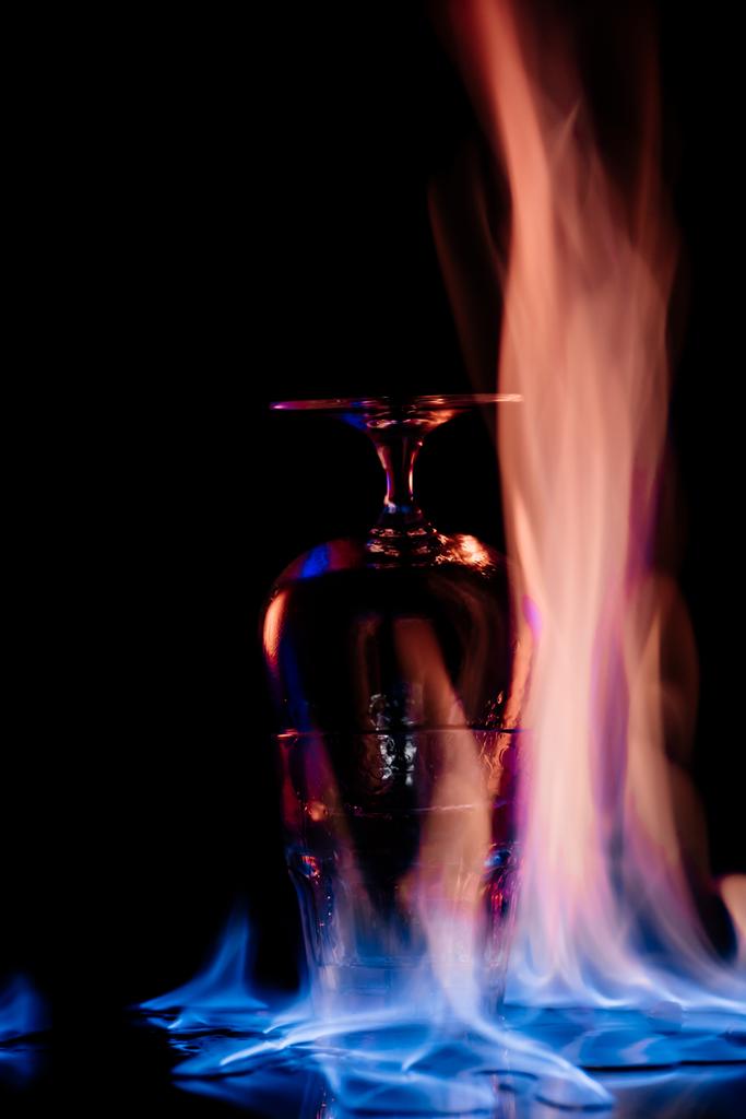 Close-up van alcohol sambuca drank in glas en vlam op zwarte achtergrond - Foto, afbeelding
