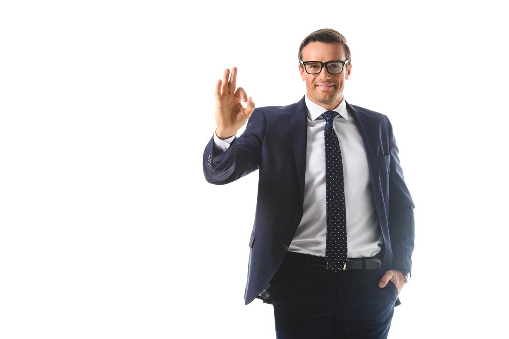lachende zakenman in brillen weergegeven: ok gebaar geïsoleerd op witte achtergrond  - Foto, afbeelding