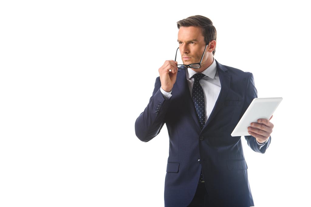 homme d'affaires sérieux ajustant les lunettes et tenant tablette numérique isolé sur fond blanc
  - Photo, image