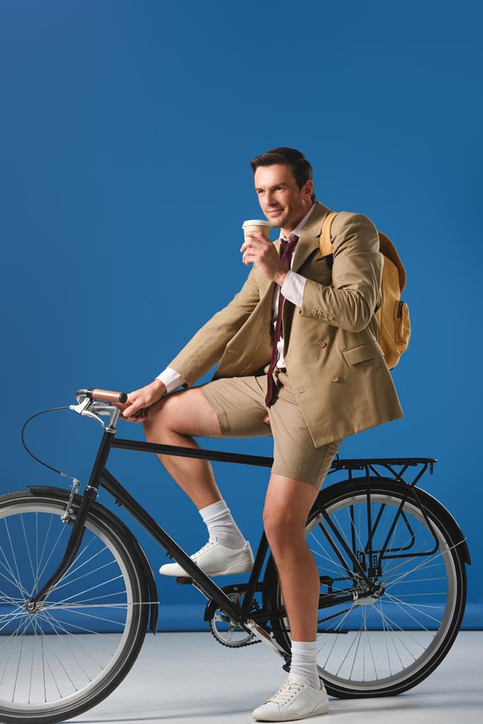 Χαμογελαστός άνθρωπος με καφέ να πάει ιππασία ποδήλατο και αναζητούν μακριά στο μπλε - Φωτογραφία, εικόνα