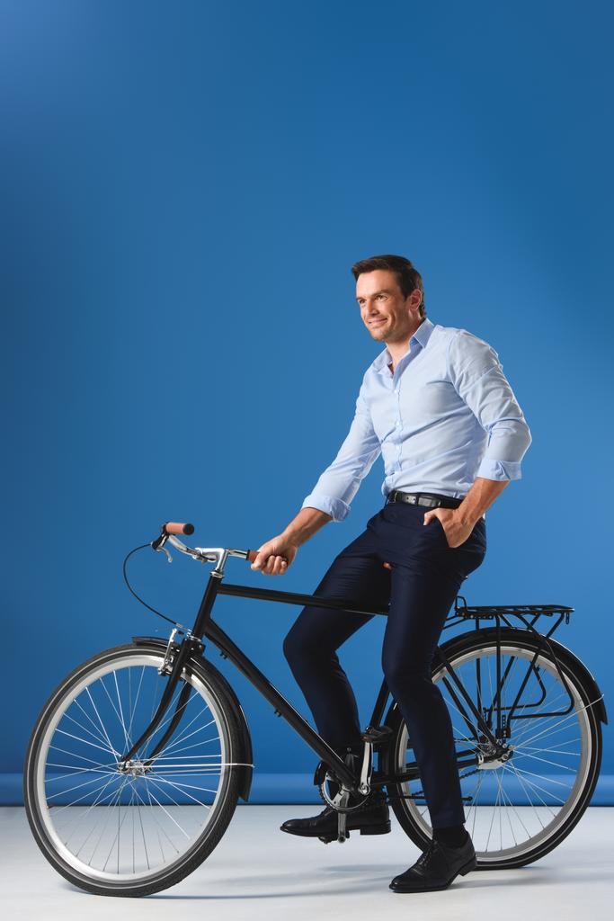 krásný usměvavý podnikatel sedí na kole a koukal na modré  - Fotografie, Obrázek