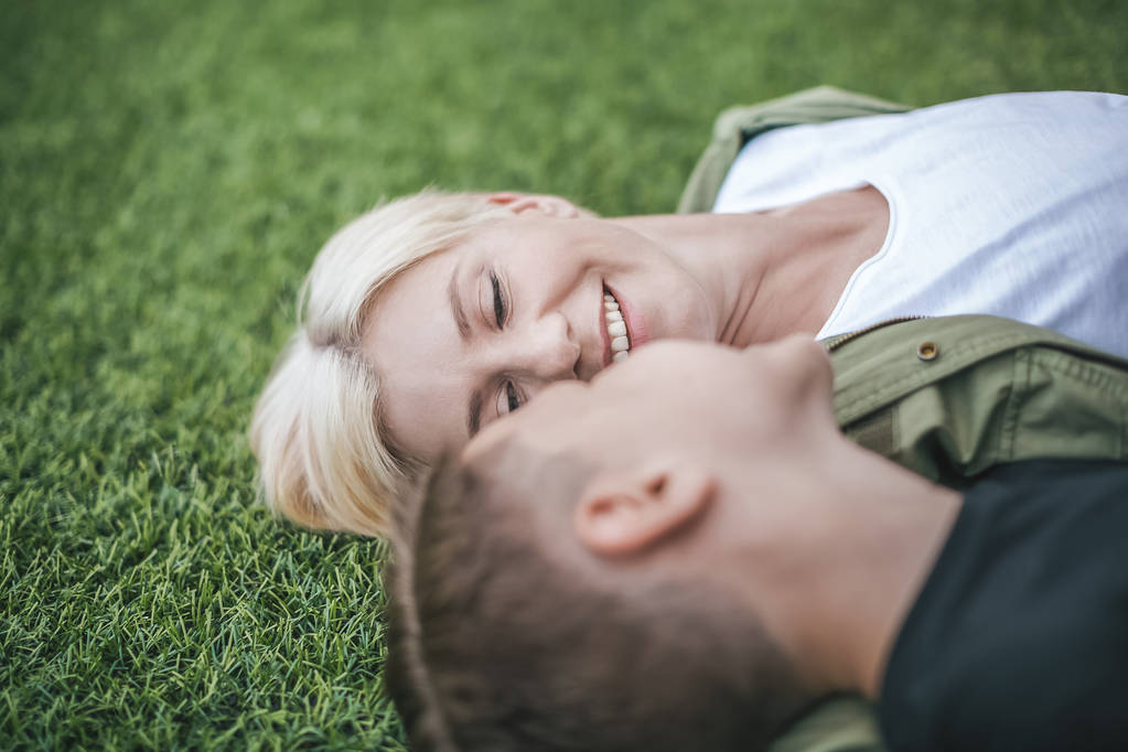 close-up view of happy mother and son lying together on grass, selective focus - Photo, Image
