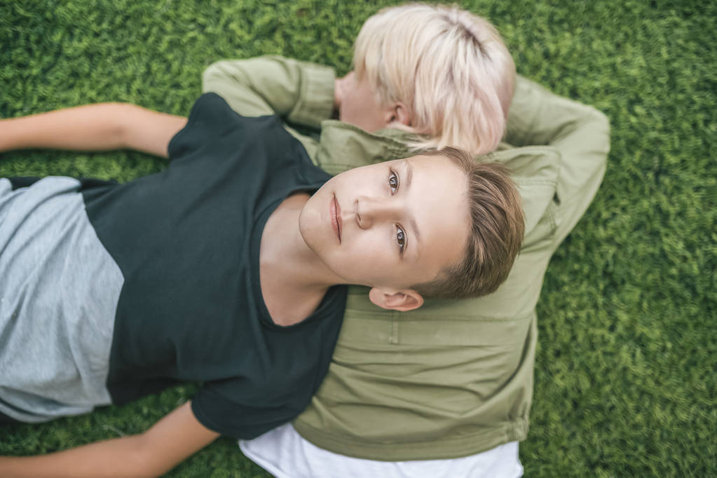 top view of beautiful mother and son lying together on green grass  - Photo, Image