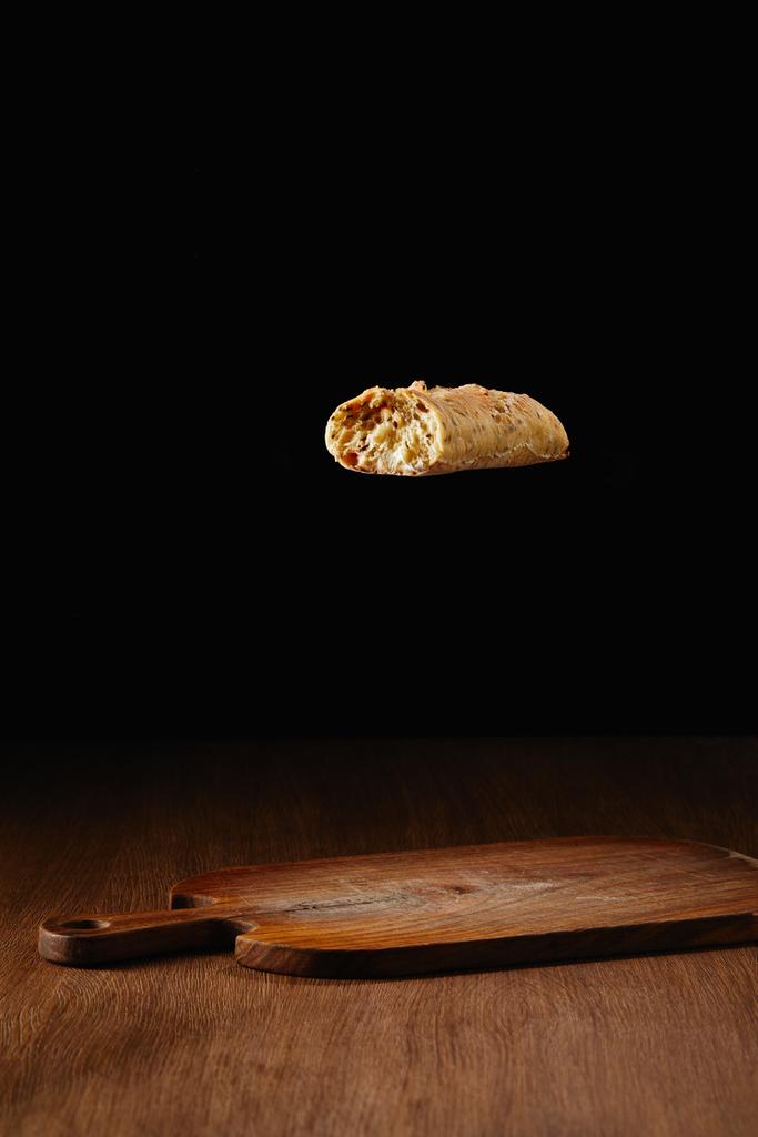 Шматок хліба, що летить над дерев'яною обробною дошкою
 - Фото, зображення