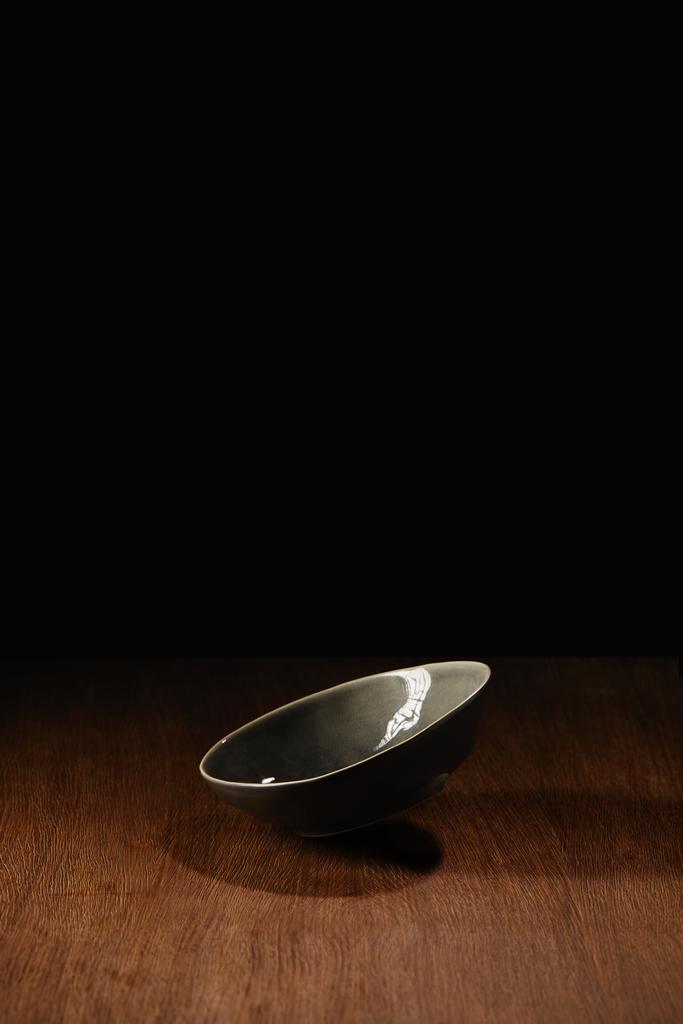 Empty ceramic bowl flying above wooden table surface - Photo, Image