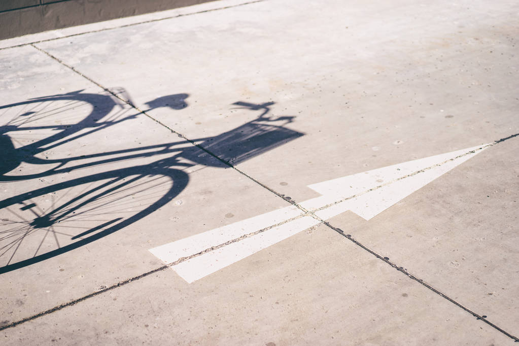 Shadow of bicycle on the ground and white arrow - Photo, Image