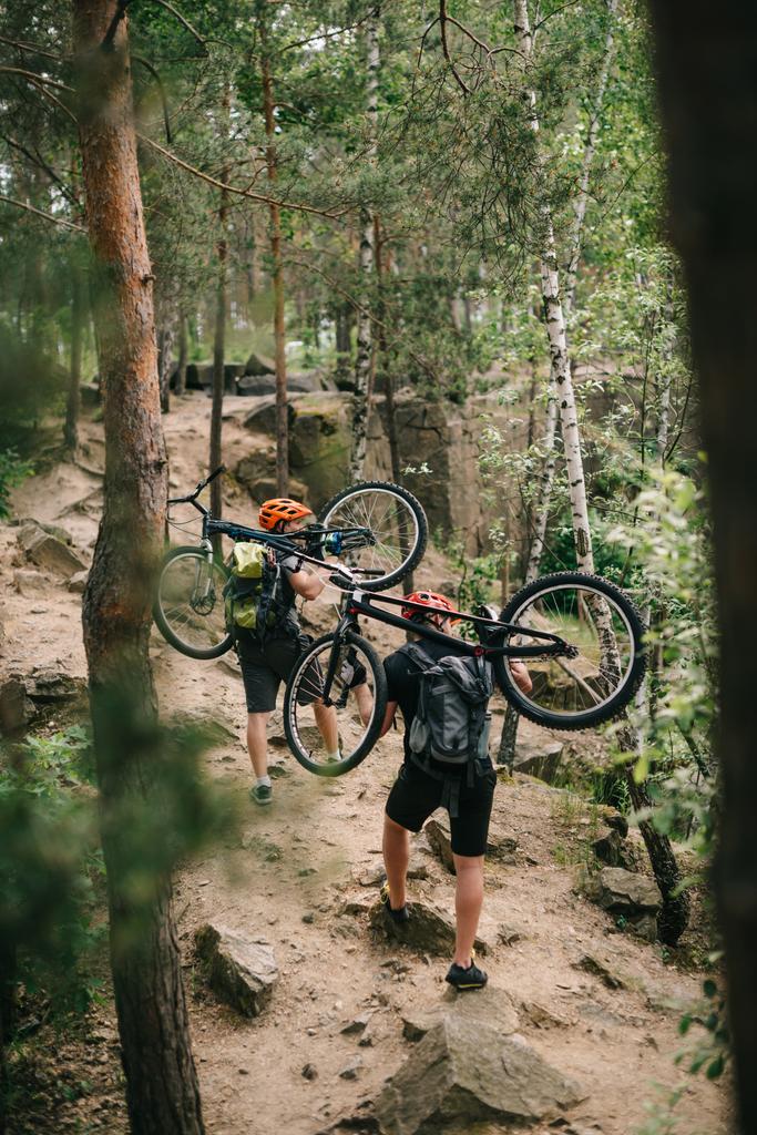 jeunes motards d'essai portant des vélos sur le dos à la forêt et monter
 - Photo, image