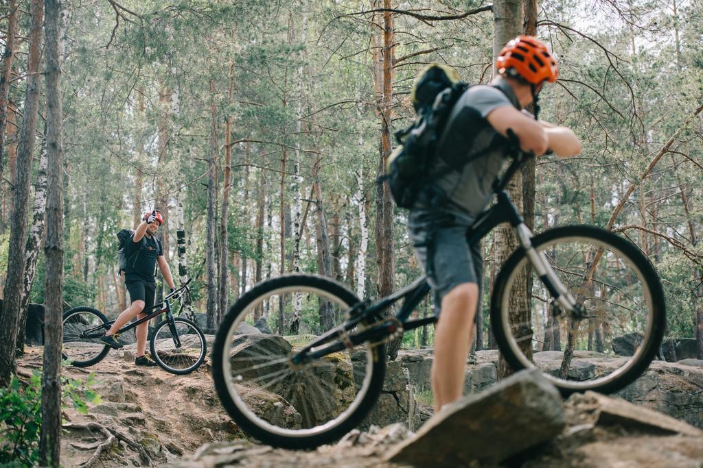 maschio estremo ciclista su mountain bike mostrando pollice in su gesto ad amico con bmx nella foresta
 - Foto, immagini