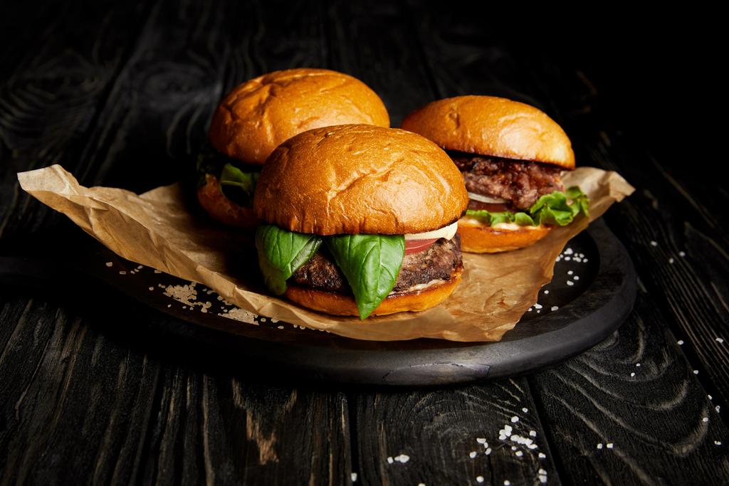 Verführerisches Fast-Food-Dinner mit drei frisch gekochten Hamburgern an Bord - Foto, Bild
