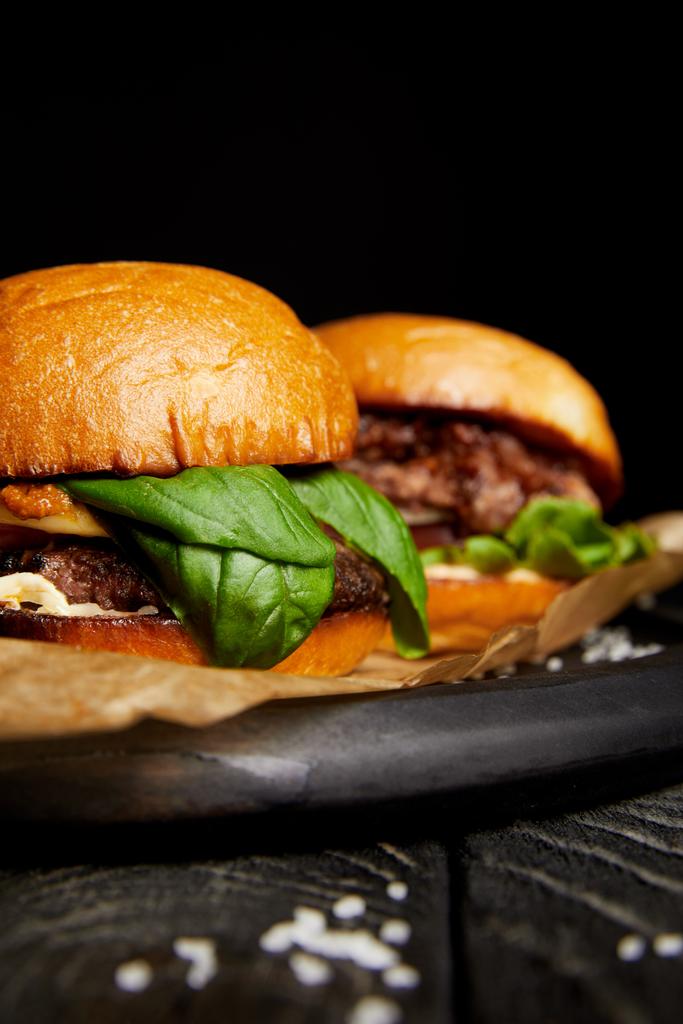Jantar de fast food tentador com deliciosos hambúrgueres quentes na tábua de madeira
 - Foto, Imagem