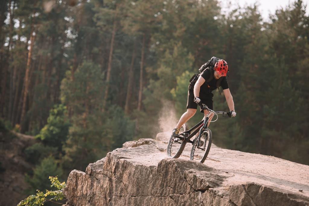 jonge proef biker rijden op rotsachtige clifff in openlucht - Foto, afbeelding