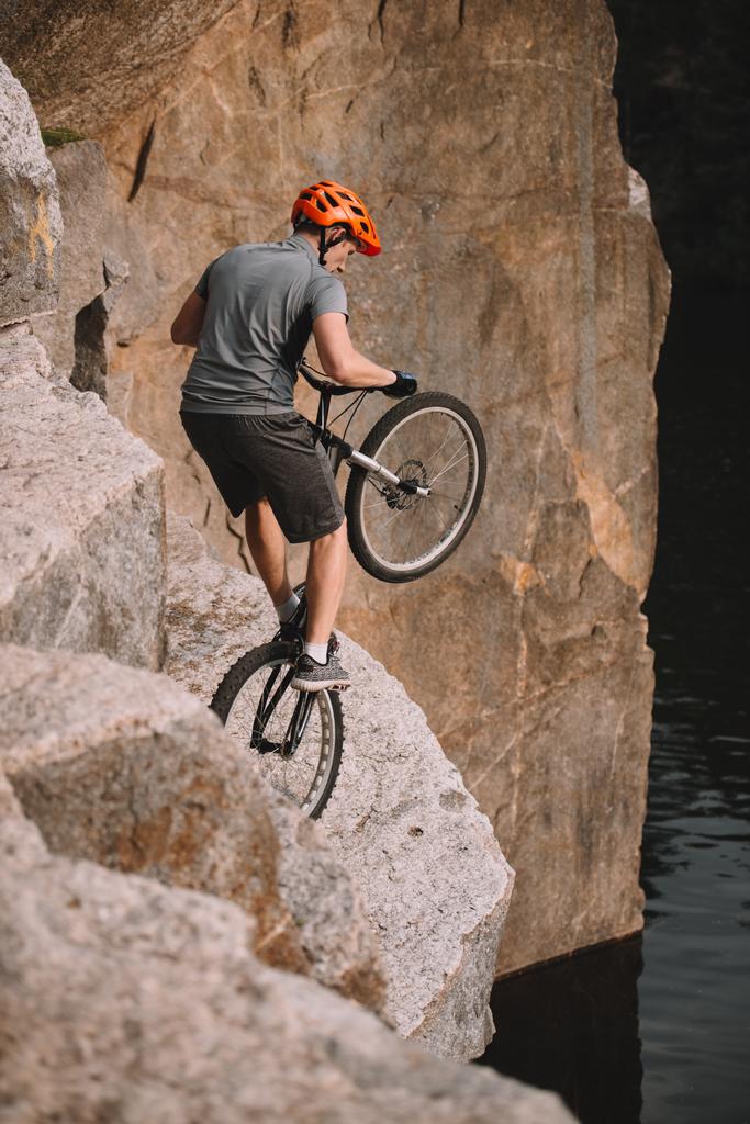 high angle view of trial biker balancing on back wheel on rocks outdoors - Photo, Image