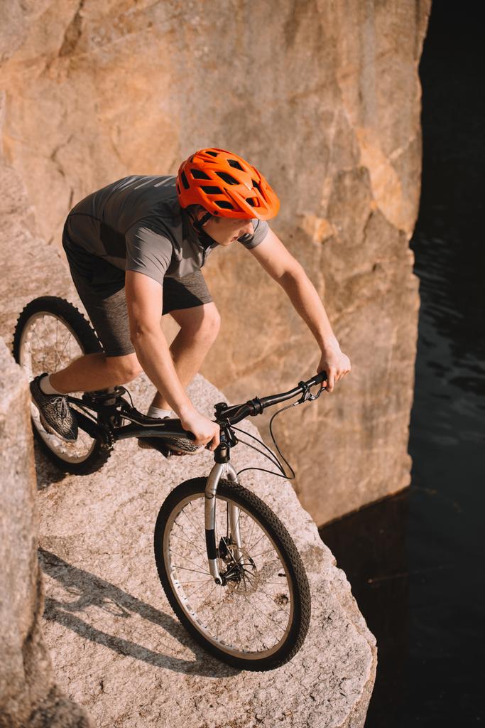 high angle view of young trial biker balancing on rocks outdoors - Photo, Image