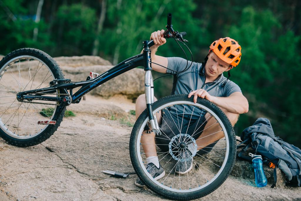 joven ciclista de trial sujetando la rueda a la bicicleta al aire libre
 - Foto, imagen