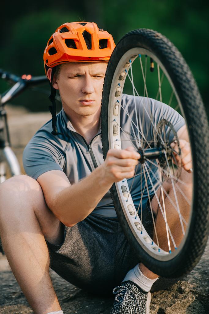 крупним планом знімок молодого пробного байкера, який вивчає велосипедне колесо на відкритому повітрі
 - Фото, зображення