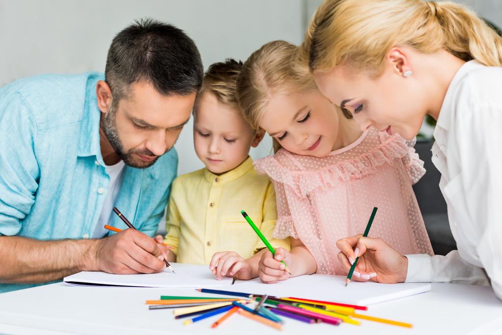 gelukkige familie tekenen met kleurpotloden samen thuis - Foto, afbeelding