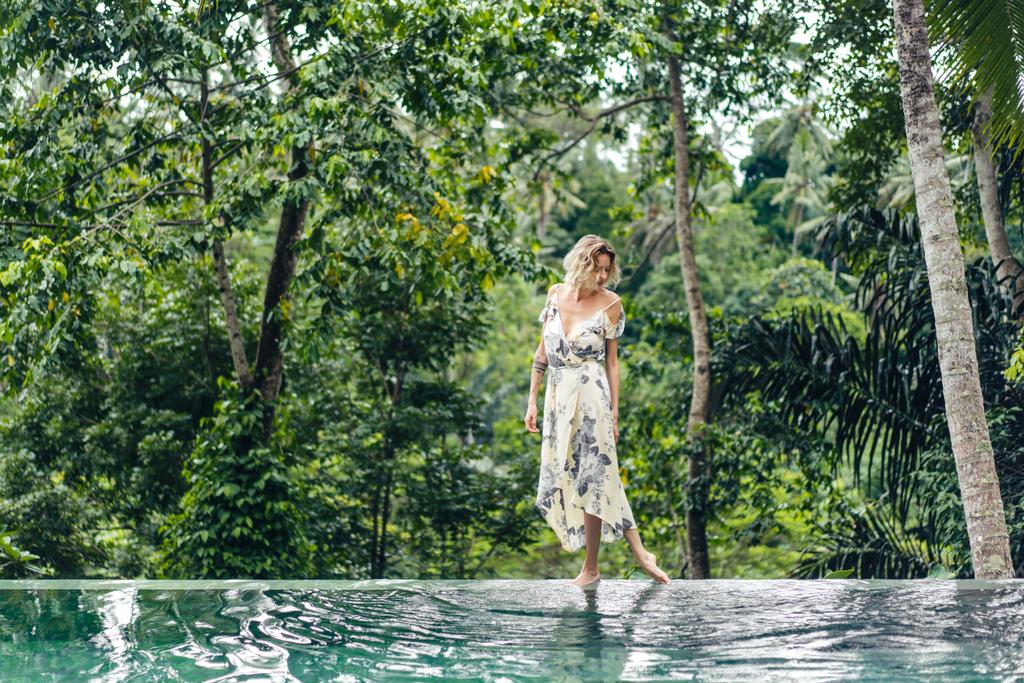 jolie femme blonde en robe marchant près de la piscine avec des plantes vertes sur le fond, ubud, bali, indonesia
 - Photo, image