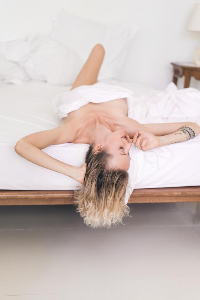όμορφη γυναίκα με τατουάζ ξαπλωμένος στο κρεβάτι - Φωτογραφία, εικόνα