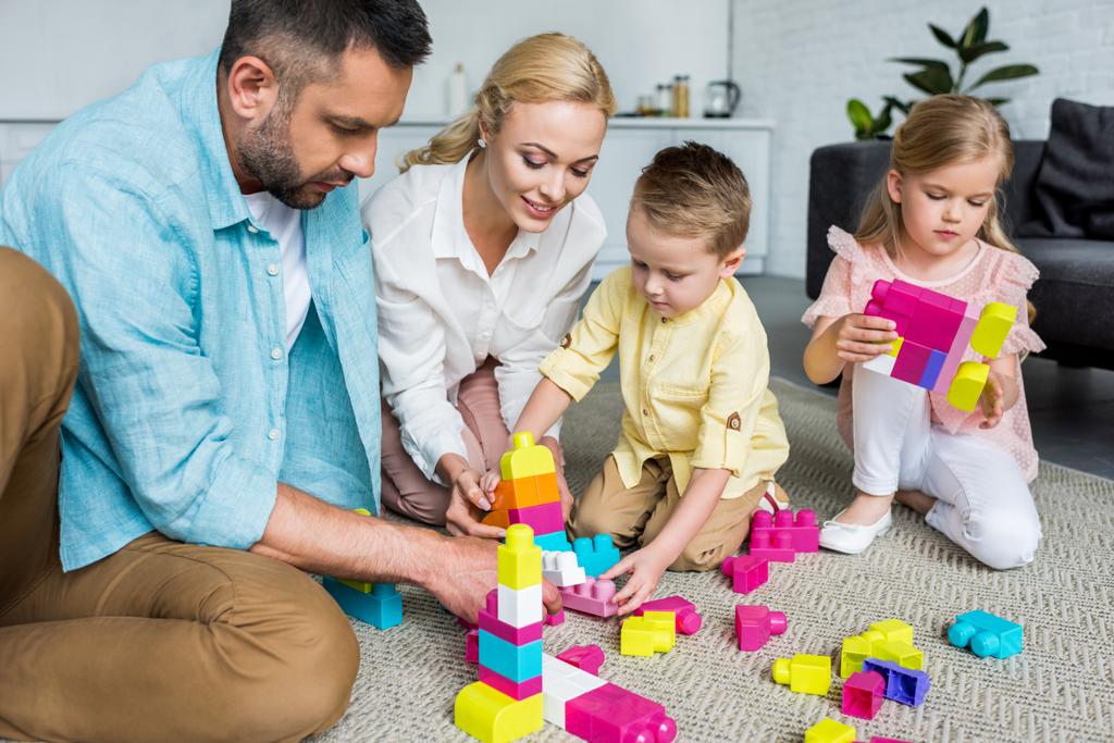 родители с очаровательными маленькими детьми, играющими с красочными блоками дома
   - Фото, изображение
