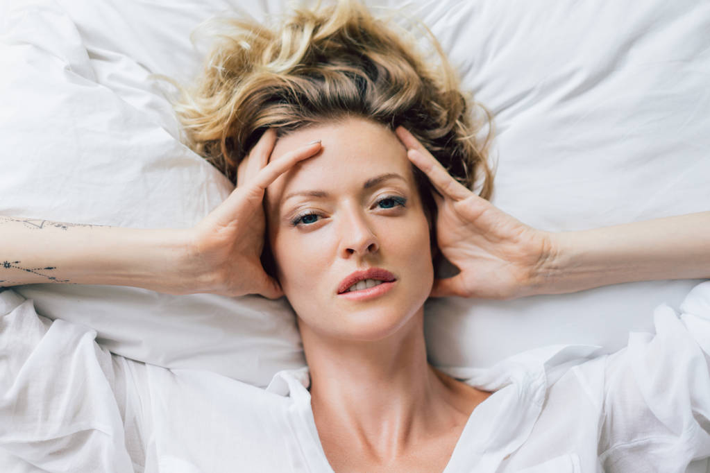 ogólny widok piękny blond kobieta w białej koszuli odpoczynku na łóżku - Zdjęcie, obraz