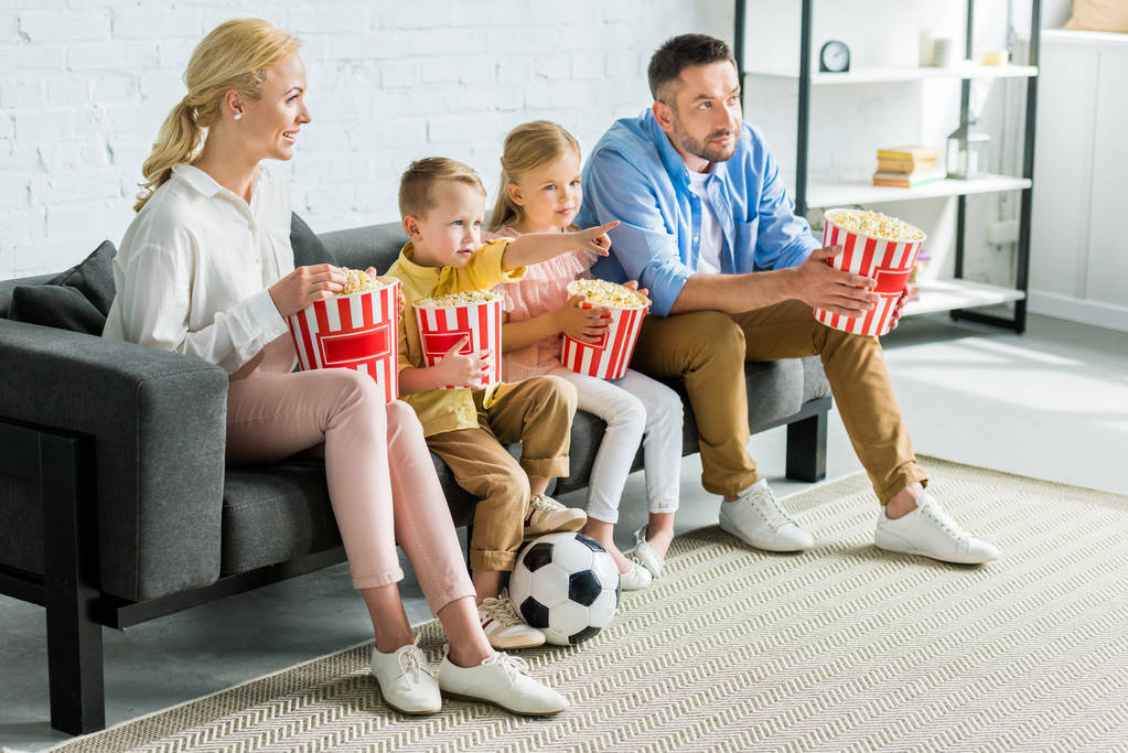 familia con dos niños comiendo palomitas de maíz y viendo la televisión en casa
 - Foto, imagen