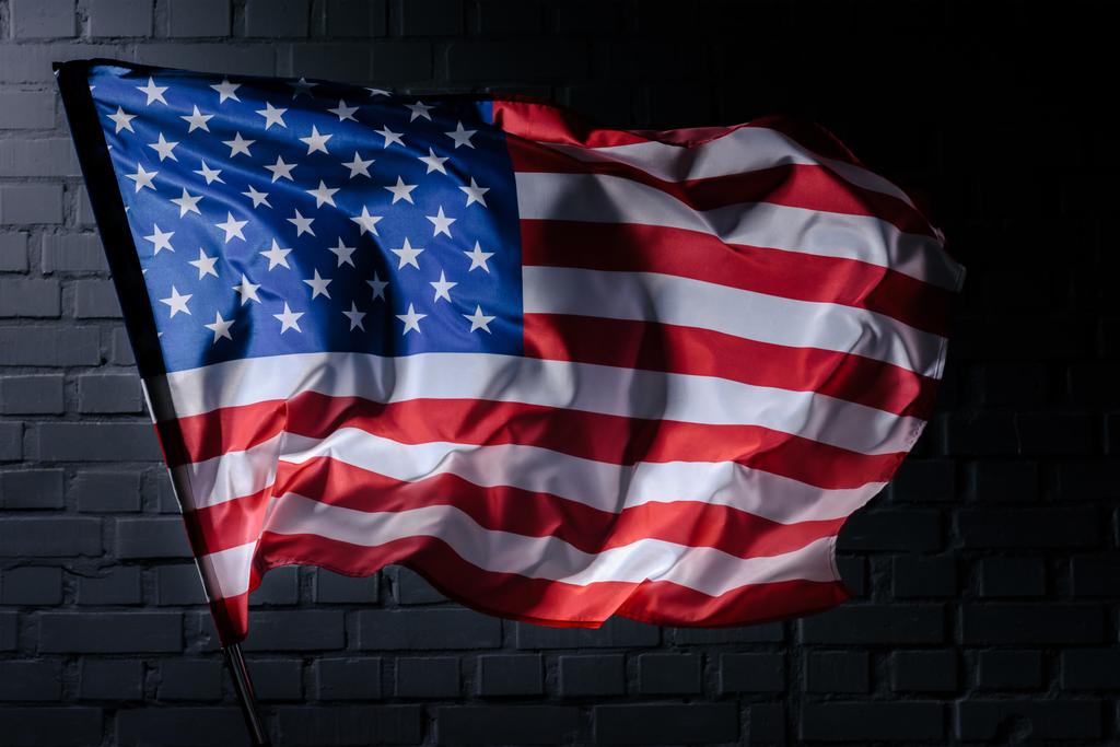 dinámica ondeando bandera de EE.UU. en frente de la pared de ladrillo negro, concepto de Día de la Independencia
 - Foto, Imagen