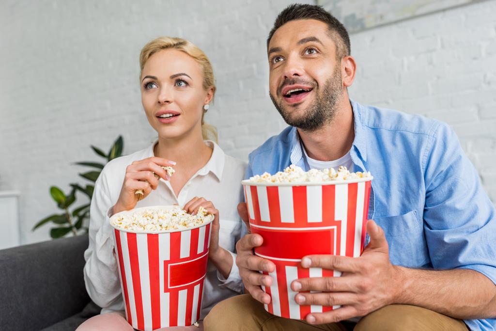 enthousiast echtpaar popcorn eten en op zoek weg thuis - Foto, afbeelding