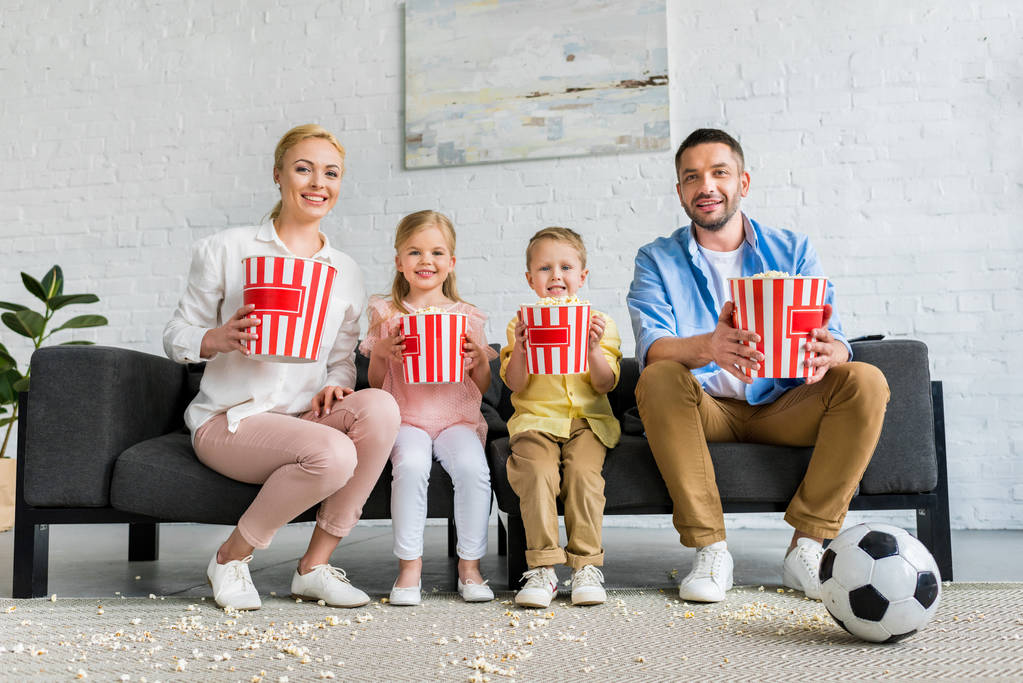 kanepede oturan ve kameraya gülümseyen mutlu ailesi popcorn ile kutuları - Fotoğraf, Görsel