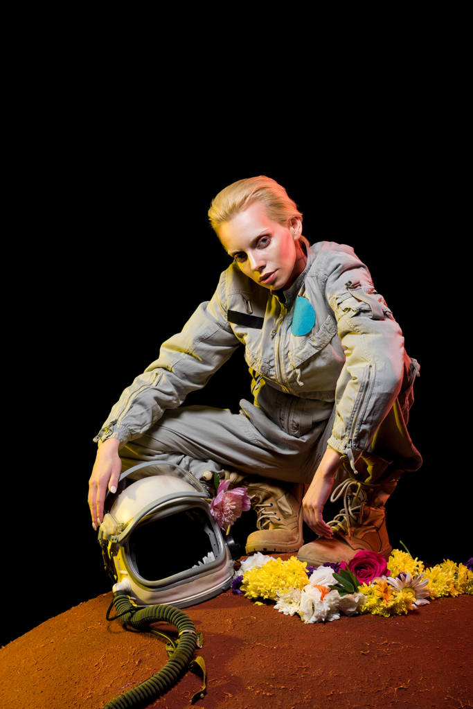 стильний космонавт в космосі з квітами і шоломом, що сидить на планеті
  - Фото, зображення