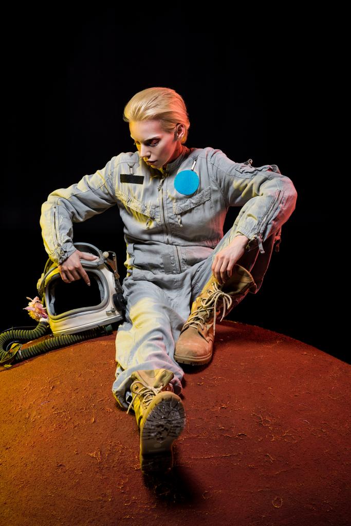 地球の上に座ってヘルメットと宇宙服の美しい宇宙飛行士 - 写真・画像
