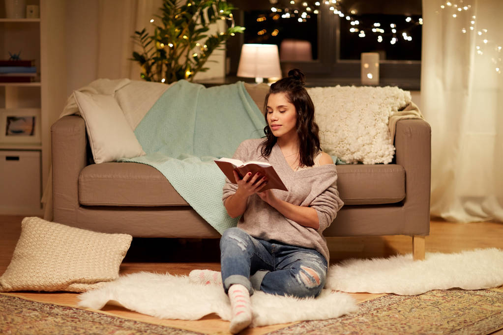 Ευτυχισμένη νεαρή γυναίκα διαβάζει βιβλίο στο σπίτι - Φωτογραφία, εικόνα