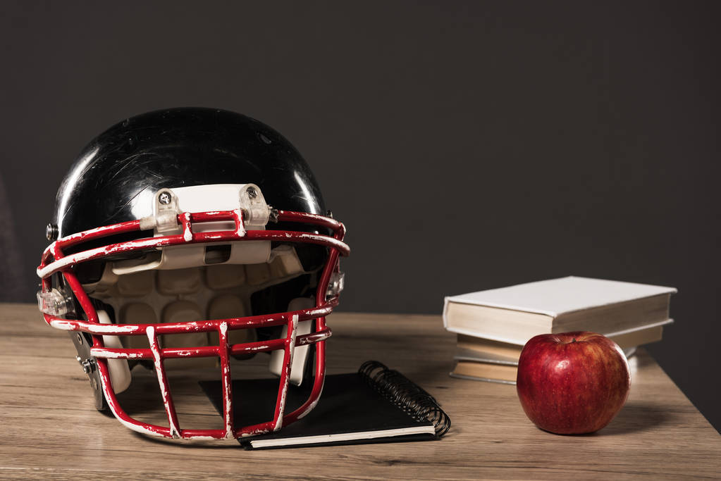 vue rapprochée du casque de football américain, manuel, pomme et pile de livres sur fond gris
  - Photo, image