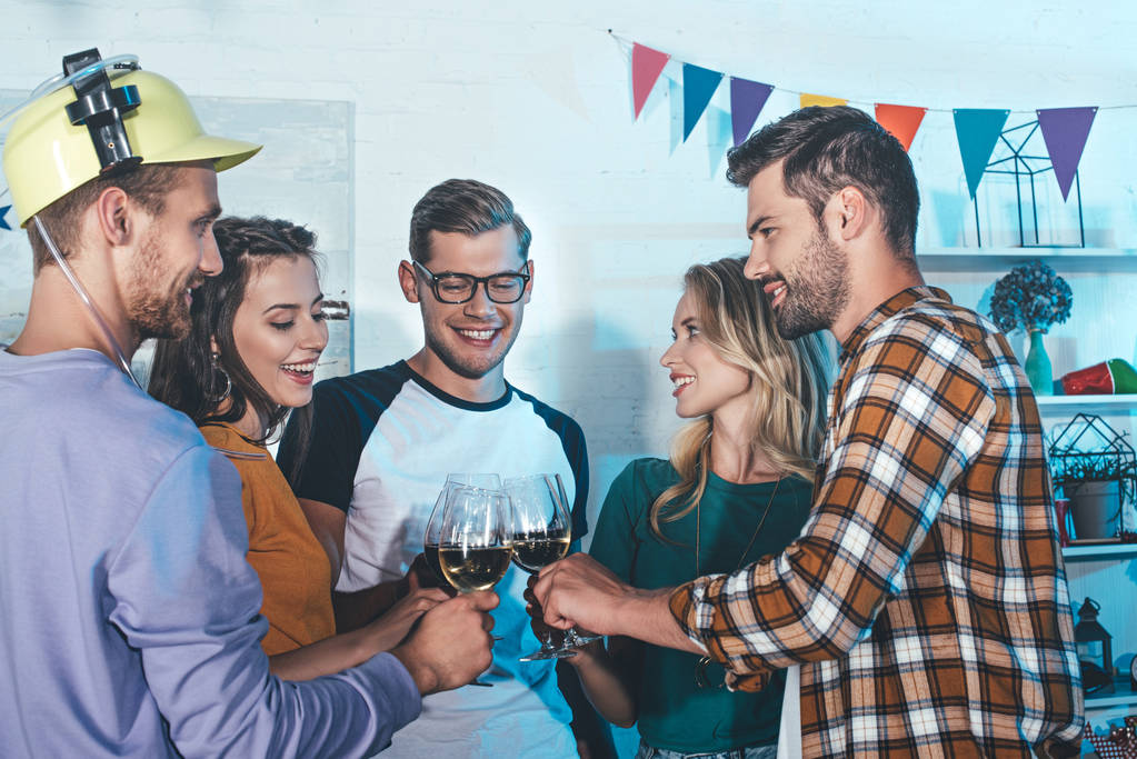 heureux jeunes hommes et femmes amis cliquetis lunettes à la maison fête
 - Photo, image