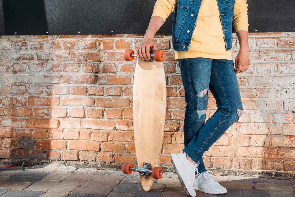 oříznutý snímek člověka s longboard stojící na ulici - Fotografie, Obrázek