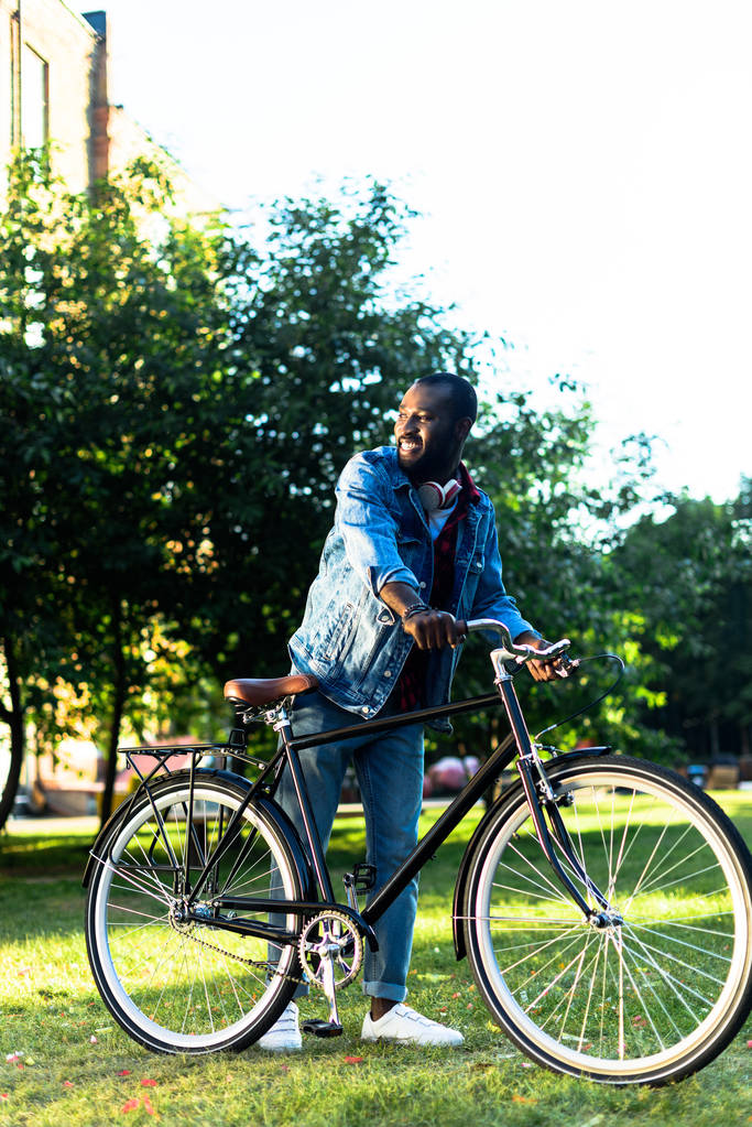 χαμογελώντας αφρικανική αμερικανική άνθρωπος με ρετρό ποδήλατο στο πάρκο - Φωτογραφία, εικόνα