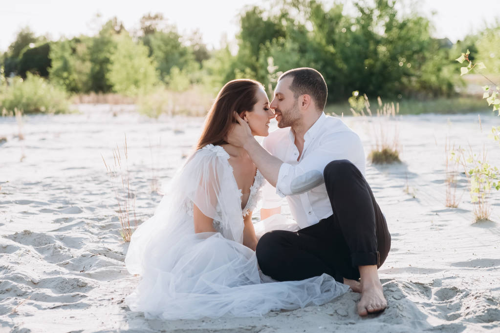 счастливая пара целуется и сидит на красивом пляже
 - Фото, изображение
