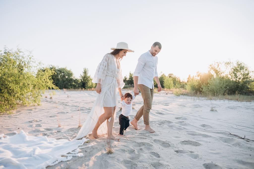 счастливая семья с сыном, держащимся за руки на пляже
 - Фото, изображение