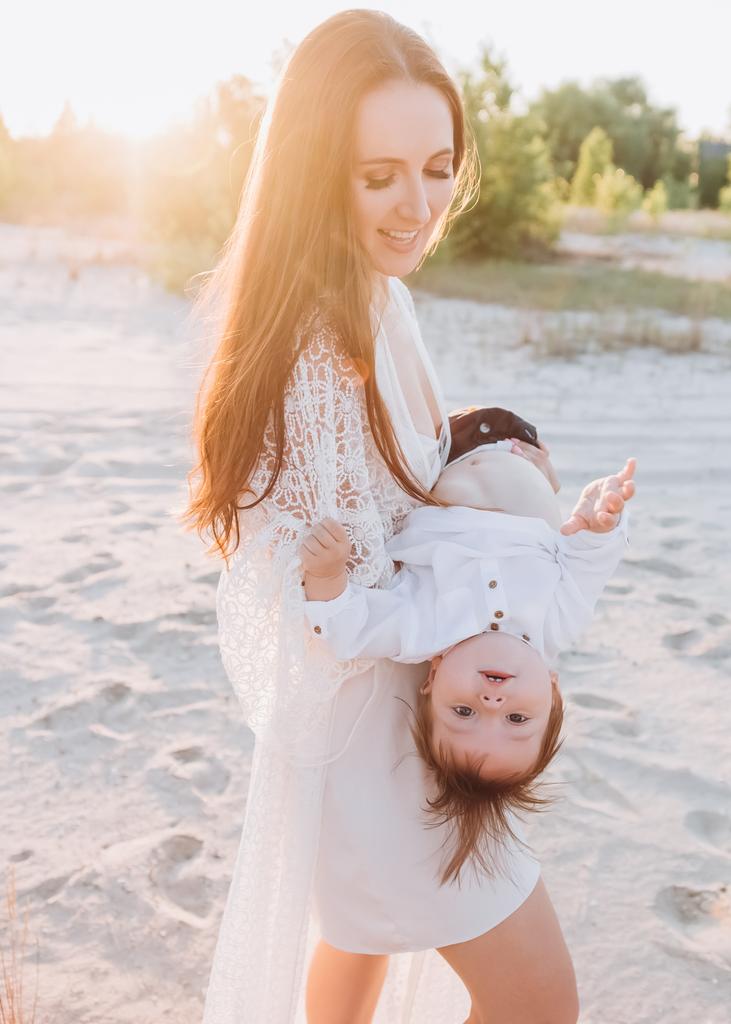 jovem mãe se divertindo com o bebê na praia
 - Foto, Imagem