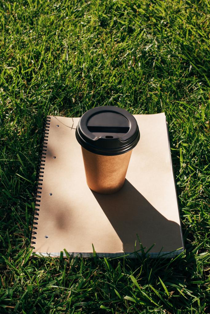 緑の草に行きコーヒーとノートブックのビューをクローズ アップ - 写真・画像