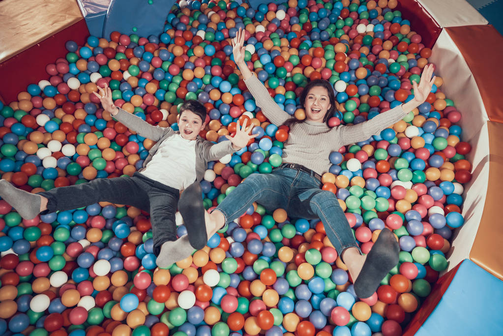 Top view. Smiling mom and son lying in pool with balls. Family rest, leisure. Spending holiday together with family. Entertainment center, mall, amusement park. - Photo, Image
