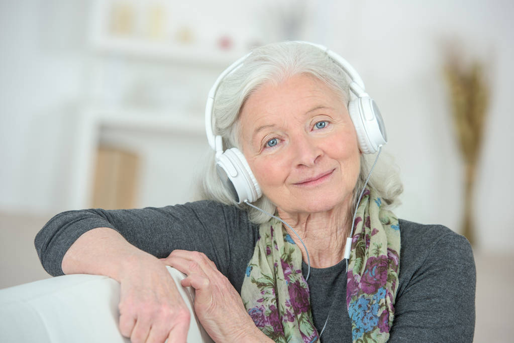 oudere vrouw luisteren naar muziek met een hoofdtelefoon - Foto, afbeelding