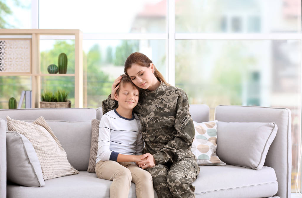 自宅のソファの上に彼女の幼い息子と軍服の女 - 写真・画像