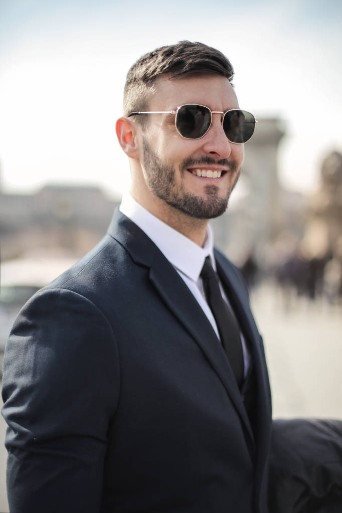 Young businessman with sunglasses looks confidently in the city. - Photo, Image
