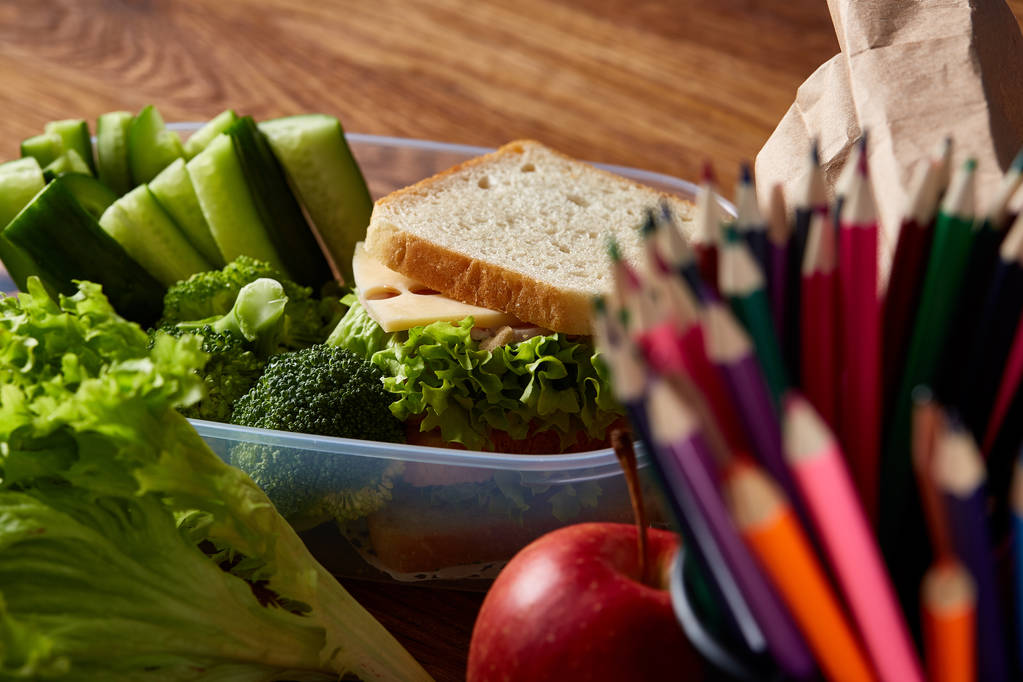 Koncepcja szkoły przerwa obiadowa z zdrowy lunch box i szkoły dostaw na biurko z drewna, Selektywny fokus. - Zdjęcie, obraz