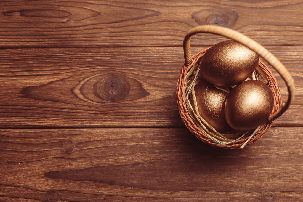 Vue du dessus des œufs en or dans le panier sur une table en bois
 - Photo, image