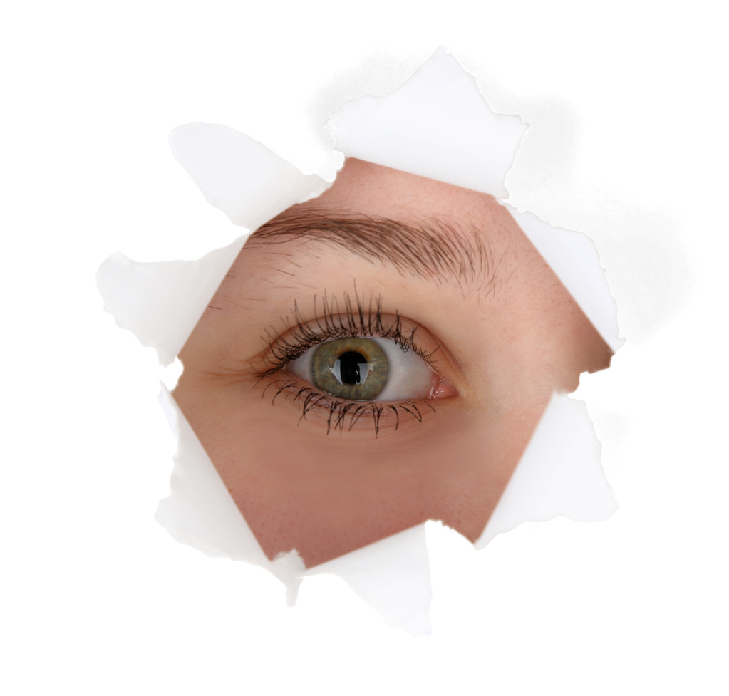 Weibliches Auge blickt durch Loch im Blatt Papier - Foto, Bild