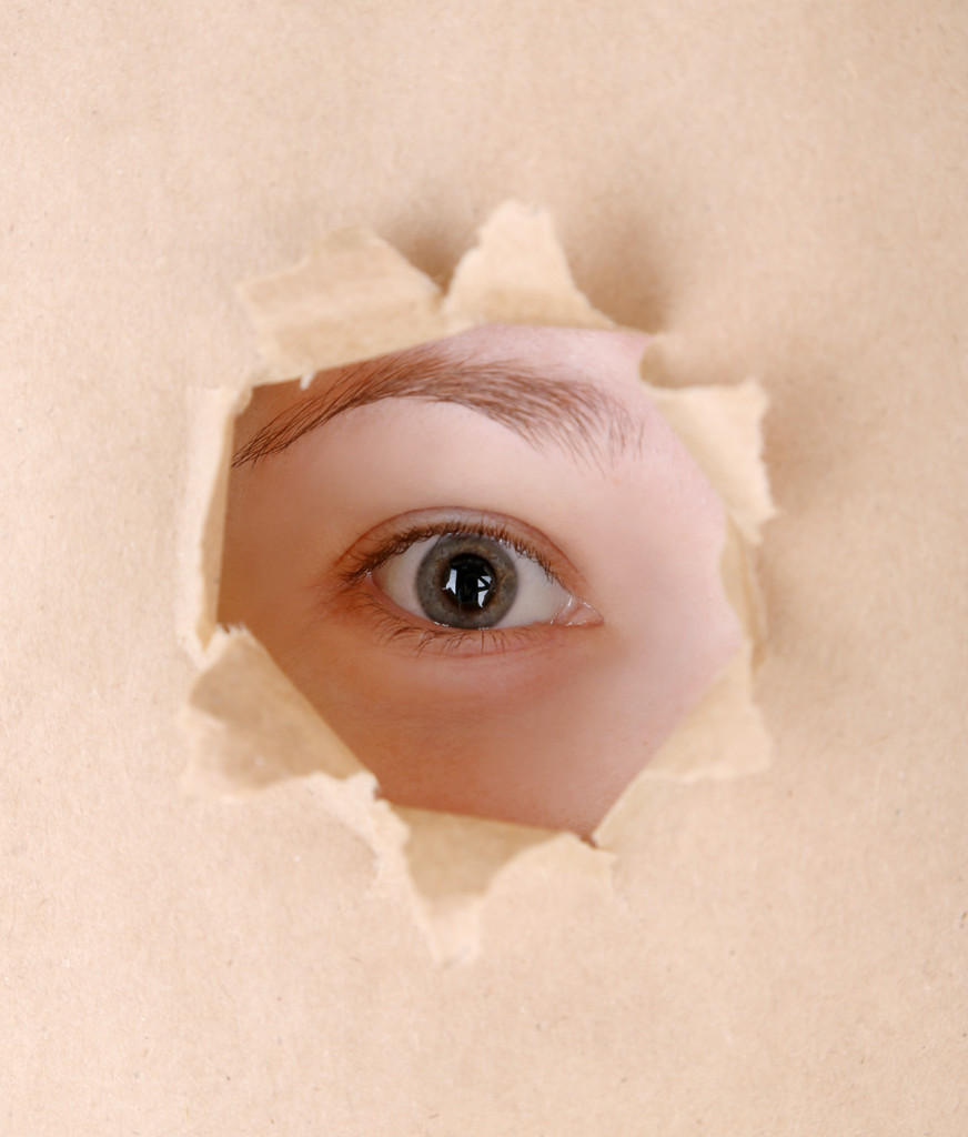 Ojo femenino mirando a través del agujero en la hoja de papel
 - Foto, Imagen