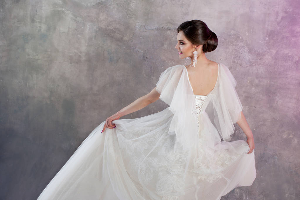 schöne und stilvolle Braut im Brautkleid im Studio auf grau strukturiertem Hintergrund - Foto, Bild