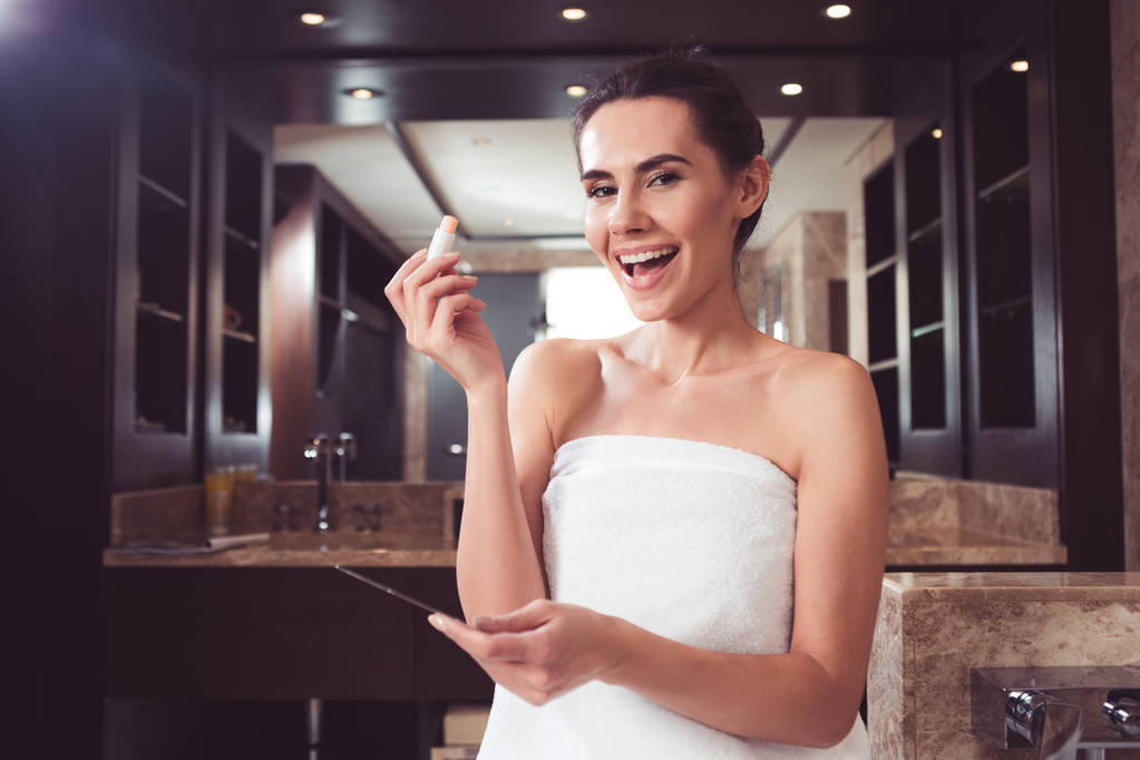 Iloinen nainen kaunistaa itseään kylpyhuoneessa
 - Valokuva, kuva
